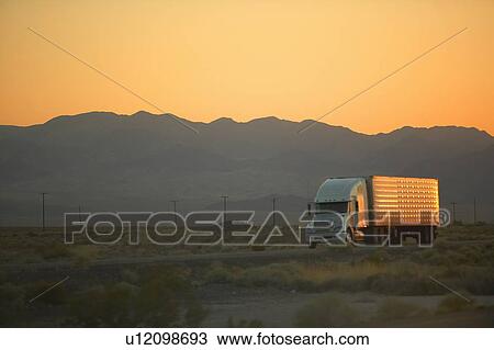 Stock Image - 18-wheeler semi-trucks at sunset. Fotosearch