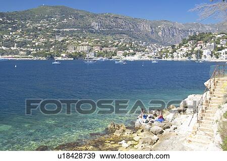 Stock Photo - Sunbathers on rocks on Mediteranean. Fotosearch