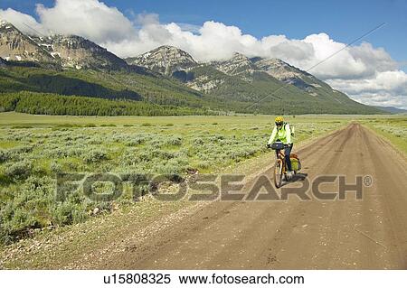 Stock Photography - Bicyclist riding through spring flowers and mountains. Fotosearch