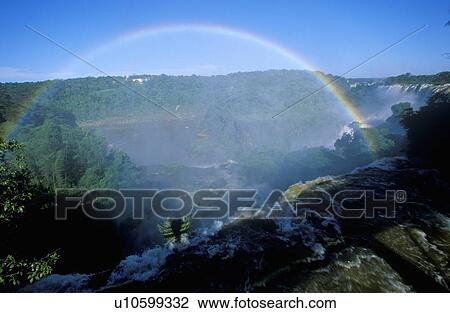 Stock Image - Complete arch rainbow over waterfall. Fotosearch