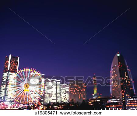 Stock Image -  Several Buildings, Skyscraper and a Ferris Wheel Illuminated at Night, Low Angle View, Defocus, Yokohama City, Kanagawa Prefecture, Japan. Fotosearch