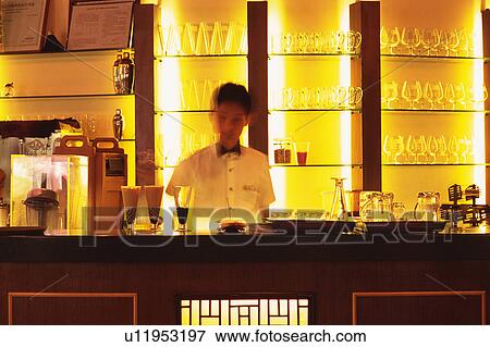 Stock Photo -  a Bartender Behind the Bar counter, Front View, Blurred Motion, Looking at Camera, Shanghai, China. Fotosearch