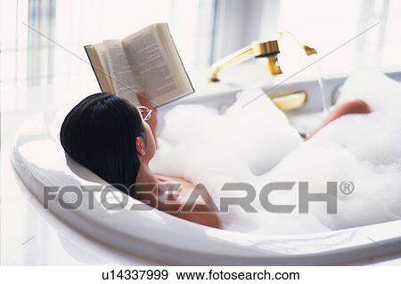 Stock Photo -  an Asian Reading a Book While Relaxing in a Bathtub Full of Foam, High Angle View, Shanghai, China. Fotosearch