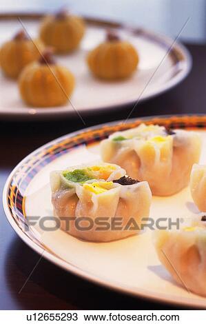 Stock Image -  Several Steamed Chinese Dumplings on a Plate, With Different Kinds of Dumplings in the Background, High Angle View, Differential Focus. Fotosearch