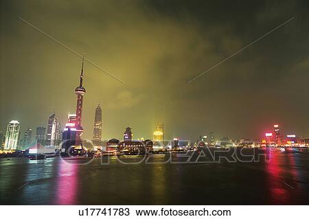 Stock Image -  Shanghai City By Night, the Buildings Illuminated, Surrounded By the Ocean Water, Shanghai, China. Fotosearch