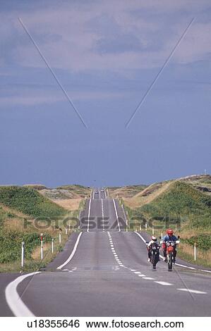 Stock Photograph -  a Long Road Surrounded By Several Hills, With Two Bikers on it, Front View, Hokkaido Prefecture, Japan. Fotosearch