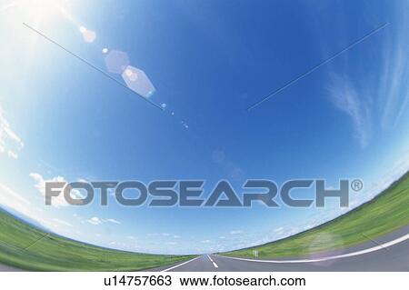 Stock Image -  a Road, Surrounded By a Green Flat Land Under a Blue Sky, Fish Eye, Lens Flare, Hokkaido Prefecture, Japan. Fotosearch