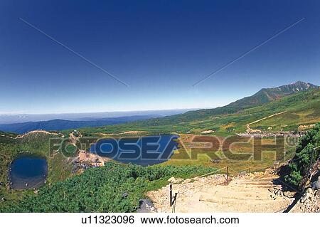 Stock Photograph -  Several Little Ponds, Surrounded By Flat Green Land and Mountains, Hokkaido Prefecture, Japan. Fotosearch