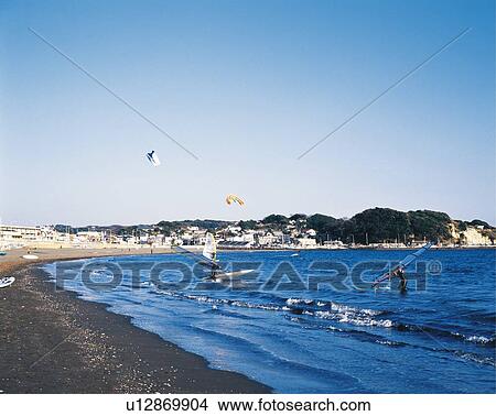 Picture - Two Surfers Carrying Surfboards in the Sea, Katasehigashi Beach, Shonan, Kanagawa Prefecture, Japan, High Angle View, Pan Focus. Fotosearch