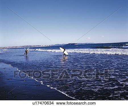 Picture - Two Surfers Walking in the Sea, Tsujido Beach, Shonan, Kanagawa Prefecture, Japan, Side View, Pan Focus. Fotosearch