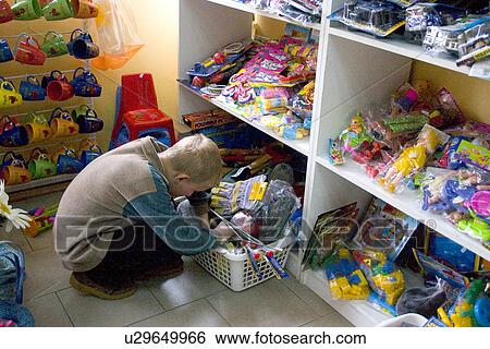 Stock Photograph - Boy looking at toys in the basket at the shop. Fotosearch