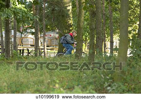 Stock Photo - Boy on bicycle ridding through the city park. Fotosearch