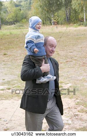 Stock Image - Happy toddler riding on grandfather's shoulder. Fotosearch