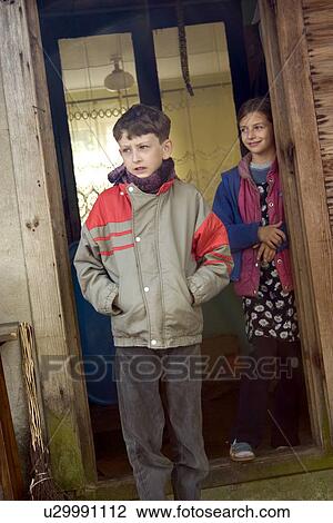 Stock Image - Polish farmers son and daughter standing in their doorway, Zawady, Central Poland. Fotosearch