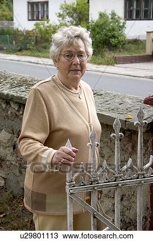 Stock Image - Polish woman at church gate, Rzeczyca, Central Poland. Fotosearch