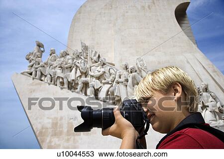 Stock Image - Caucasian boy looking through camera at the Monument to the Discoveries in Lisbon, Portugal.. Fotosearch