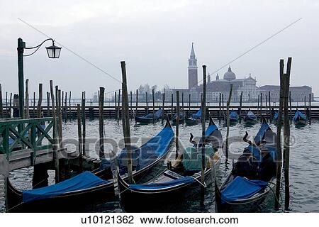 Stock Image - Gondolas moored at canal side Canal di San Marco. Fotosearch