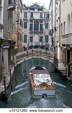 Stock Image - Motor boat in early morning light on canal. Fotosearch