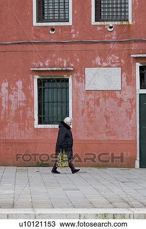 Stock Image - Person in winter coat with flowered carrying bag. Fotosearch