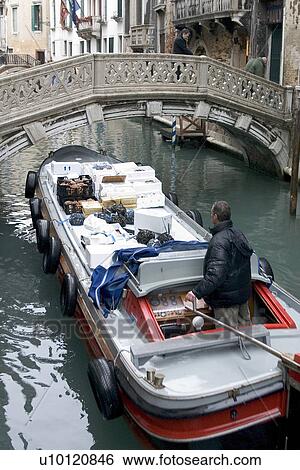 Stock Photograph - Red barge on canal approaching bridge with delivery of seafood. Fotosearch