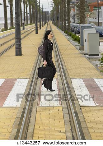 Businesswoman walking across pedestrian crossing on tramway View Large Photo Image Stock Photo - Businesswoman walking across pedestrian crossing on tramway. Fotosearch