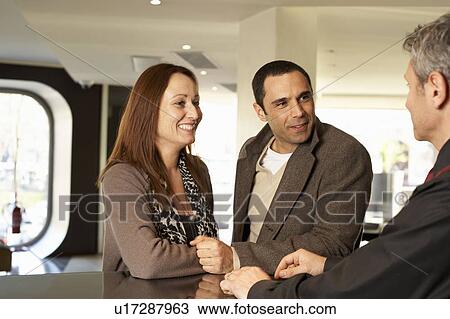 Couple in hotel talking to concierge View Large Photo Image Stock Image - Couple in hotel talking to concierge. Fotosearch