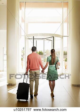 Couple leaving hotel with luggage, rear view View Large Photo Image Stock Photo - Couple leaving hotel with luggage, rear view. Fotosearch