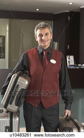 Portrait Hotel porter holding luggage View Large Photo Image Stock Image - Portrait Hotel porter holding luggage. Fotosearch