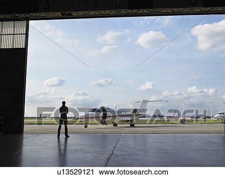Technician in hangar looking at private jet on tarmac. View Large Photo Image Stock Image - Technician in hangar looking at private jet on tarmac.. Fotosearch