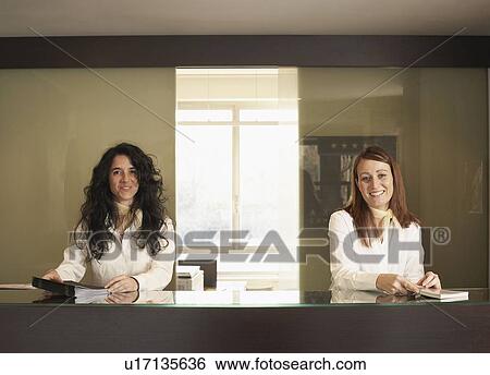 Stock Photograph - Two Receptionists behind hotel counter. Fotosearch