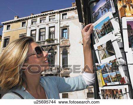 Picture - Woman choosing a postcard, smiling. Fotosearch