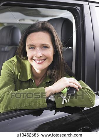 Stock Photography - Woman in a car, holding keys, smiling. Fotosearch