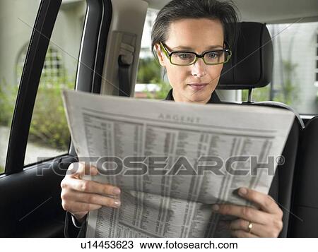 Woman in car, reading newspaper View Large Photo Image Stock Image - Woman in car, reading newspaper. Fotosearch