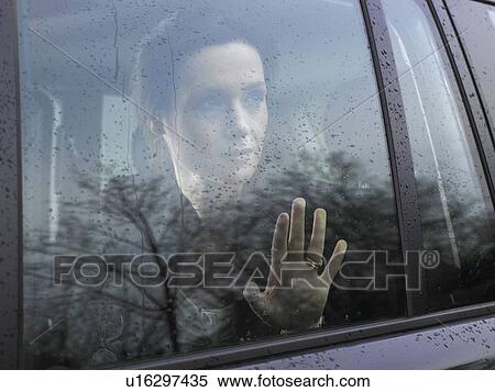 Stock Photography - Woman looking through a car's window. Fotosearch