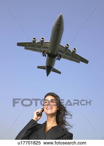 Woman on cellular phone smiling with plane flying overhead. View Large Photo Image Stock Photography - Woman on cellular phone smiling with plane flying overhead.. Fotosearch