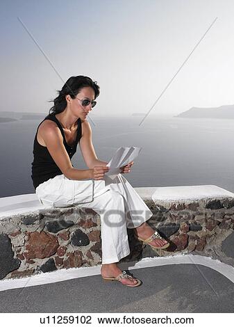 Woman reading a letter on a low wall View Large Photo Image Stock Image - Woman reading a letter on a low wall. Fotosearch