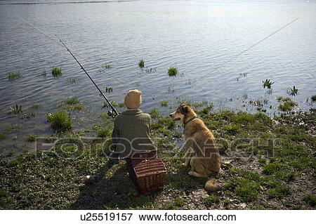 Boy (12-14) fishing by river with pet dog, rear view View Large Photo Image Stock Photo - Boy (12-14) fishing by river with pet dog, rear view. Fotosearch