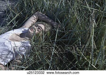 Young woman lying in long grass. View Large Photo Image Stock Image - Young woman lying in long grass.. Fotosearch