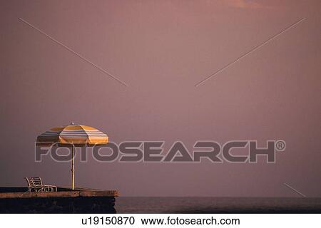 Stock Image - Beach Umbrella and Deckchair by Sea. Fotosearch