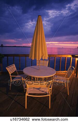 Stock Image - Table, Chair and Beach Umbrella on Deck, High Angle View. Fotosearch