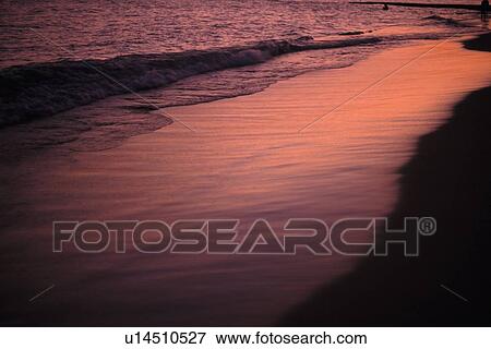 Stock Photo - The Beach Tinged with Orange by the Setting Sunlight, High Angle View. Fotosearch