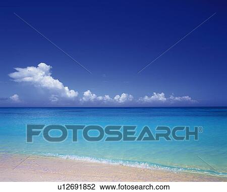 Stock Image - Tropical Beach and the Clouds Sailing in the Blue Sky, Pan Focus. Fotosearch