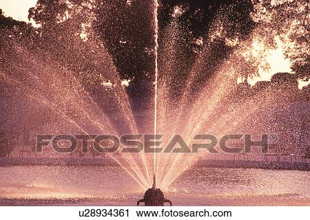 Stock Image - Image of a Fountain in Paris, the Water Reflecting the Colors of the Setting Sun, Front View, Paris, France. Fotosearch