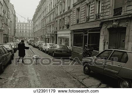 Stock Photo - Image of a Typical French Street, a Woman Taking her Dog for a Walk, Front View, Paris, France. Fotosearch