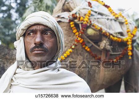 Stock Photo - Close-up of a mid adult man standing with a camel. Fotosearch