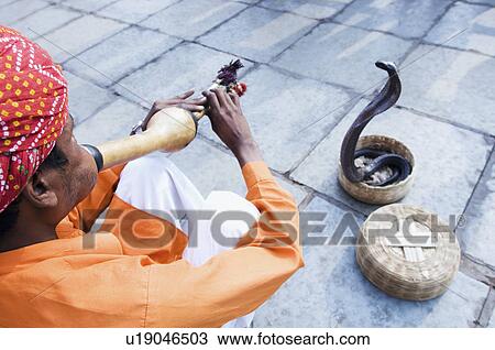 Stock Image - High angle view of a snake charmer playing the flute, Jaipur, Rajasthan, India. Fotosearch