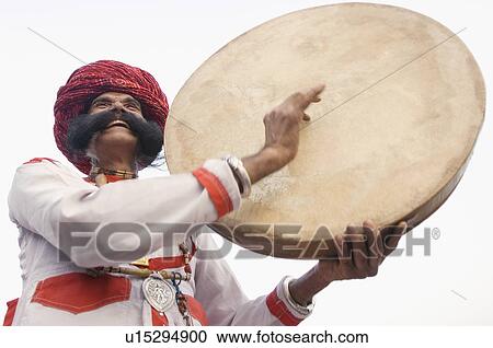 Stock Image - Low angle view of a mature man playing a drum, Elephant Festival, Jaipur, Rajasthan, India. Fotosearch