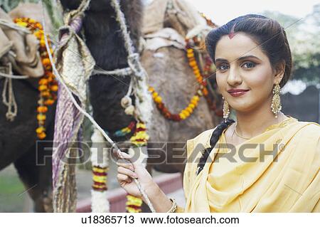Stock Image - Portrait of a young woman holding the reins of a camel. Fotosearch