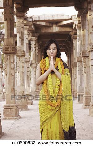 Portrait of a young woman standing in a prayer position wearing garlands View Large Photo Image Stock Image - Portrait of a young woman standing in a prayer position wearing garlands. Fotosearch