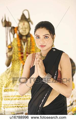 Portrait of a young woman standing in a prayer position in front of an idol of Lord Shiva View Large Photo Image Stock Photograph - Portrait of a young woman standing in a prayer position in front of an idol of Lord Shiva. Fotosearch